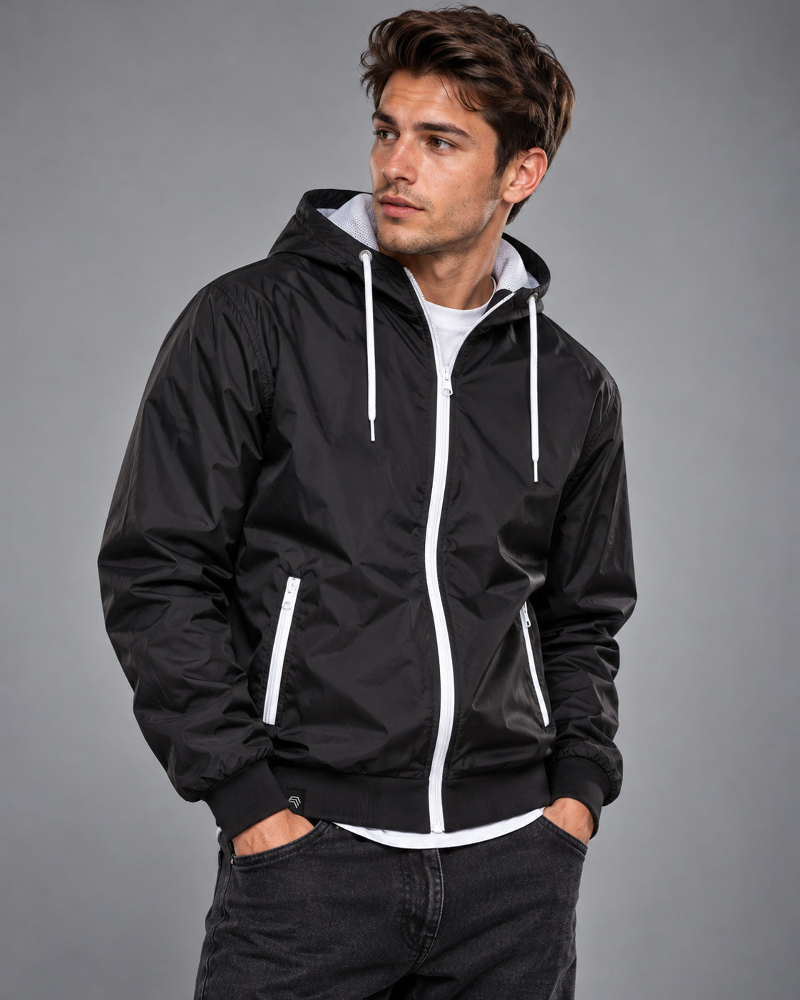 Schwarzer Windbreaker BBD 6100 in Black / White an männlichem Model in lässiger Dreiviertelpose – weiße Reißverschlüsse an Front und Taschen, weiße Kapuzenkordeln und sichtbares helles Mesh-Innenfutter.