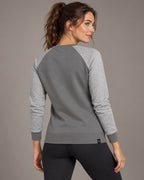 Grau Solid / Melange – zweifarbiges Damen-Raglansweatshirt am Model in Dreiviertel-Rückenansicht, mit hellgrau melierten Ärmeln, diagonalen Rückennähten und breitem Rippbund.