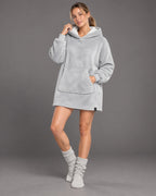 Snow Light Grau – Produktcollage des flauschigen Sherpa-Fleece-Ponchos mit Frauenmodel und Detailaufnahmen von Kapuzenöffnung, Saumnaht und Ärmelbündchen