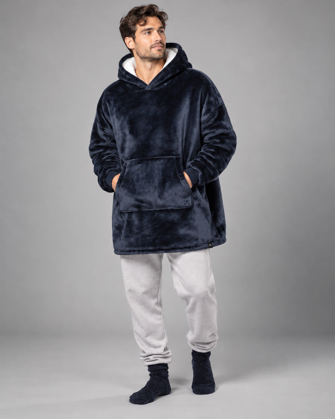 BRK 014K Unisex Kapuzenponcho in Navy Night Blau am männlichen Model, großzügiger Oversize-Schnitt mit Kängurutasche und Sherpa-Kapuze im Studio